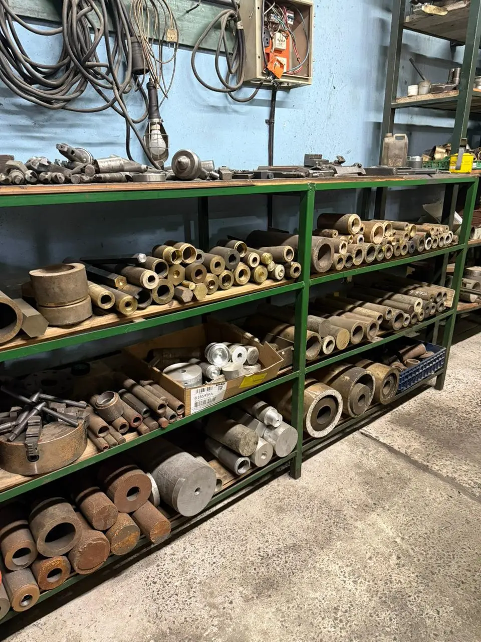 Estantería del taller con bujes y barras de bronce y fundición de hierro